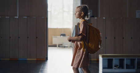 Wall Mural - Schoolgirl walking holding books in empty hall alone. Pupil passing classrooms.
