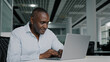 © Yuliia - African american businessman work on laptop at office chatting online young woman trainee come to adult colleague analyze startup internet project approve commercial idea thumb up agreeing shake hands