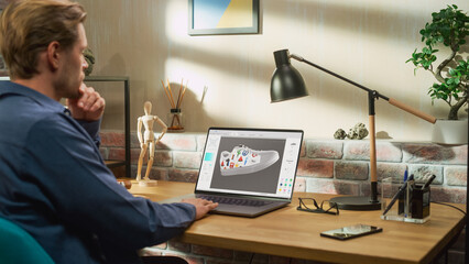 Poster - Young Male Footwear Designer Works on 3d Model of Shoe and Change Colours on It While Working on Laptop Computer in Creative Space. Fashionable Shoe Production Procedure Concept.