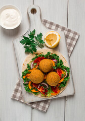 Wall Mural - Tortillas, wrapped falafel balls, with fresh vegetables, vegetarian healthy food, on a wooden white background, no people, selective focus.