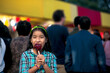 © SALMONNEGRO - A happy girl eating caramel apple at a fair.