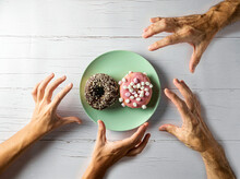 Unrecognizable People Pick Up A Donut From A Plate On A Wooden Table. Top View Of The Placement In Plan