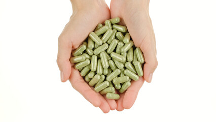 Wall Mural - Female hands hold green capsule with superfoods moringa or spirulina, isolated on white background