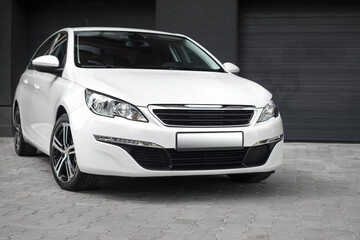 Compact white executive car, with beautiful wheels, large chrome grille. Modern white car.