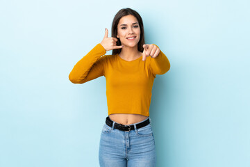 Wall Mural - Young caucasian woman isolated on blue background making phone gesture and pointing front