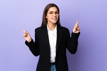 Wall Mural - Business woman isolated on purple background pointing finger to the laterals and happy