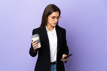 Sticker - Business woman isolated on purple background holding coffee to take away and a mobile