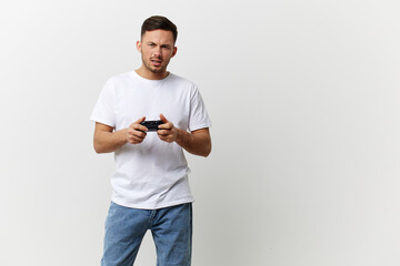 Wall Mural - Confused irritated tanned handsome man in basic t-shirt failed game session with joystick gamepad posing isolated on over white studio background. Copy space Banner Mockup. Gamer RPG concept