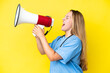 © luismolinero - Young surgeon nurse woman isolated on yellow background shouting through a megaphone