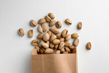 Overturned Paper Bag With Pistachio Nuts On White Background, Flat Lay