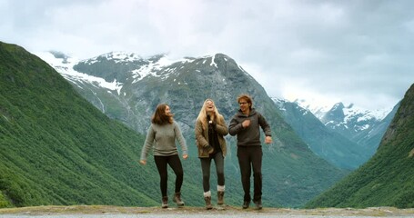happy, excited and hiking friends dancing on mountain or snow green hills outdoors with beautiful na