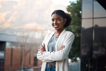 Confident business woman with arms crossed standing outside of an office at work. Portrait of one happy, smiling and expert corporate professional with arms folded working at a startup company