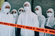 © N Felix/peopleimages.com - Covid, pandemic and team doctors, scientists or heathcare workers wearing protective ppe to prevent virus spread at a quarantine site. First responders wearing hazmat suits while standing behind tape
