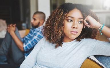 Poster - Unhappy, angry and stressed couple sitting on a sofa together after arguing. Young african american man and woman looking annoyed and ready for divorce while experiencing relationship problems