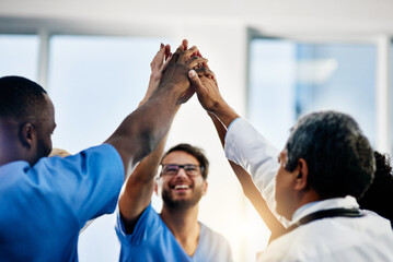 Doctors celebrating medical success after working together as a team and give each other motivating a high five as a group in a hospital. Healthcare workers joining hands in a huddle showing teamwork