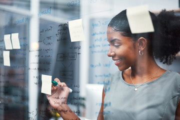 Happy, inspired and confident business woman brainstorming ideas, writing on transparent glass board with sticky notes. Powerful entrepreneur and CEO leading startup, planning company strategy.