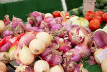 A View Of A Table Full Of Assorted Onions, On Display At A Local Farmers Market.