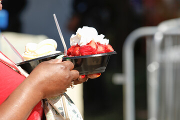 A view of a patron carrying a bowl of strawberry shortcake, a featured street food item at the Strawberry Festival, in Garden Grove, California.