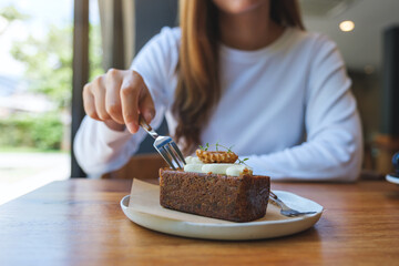 Wall Mural - Closeup image of a woman eating a piece of carrot cake with fork