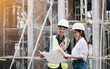 © wichayada - asian architect and mature supervisor meeting at construction site.  worker and engineer discussing on plan. Two construction workers working together while visiting a new building.