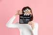Beautiful girl with movie clapperboard on pink background