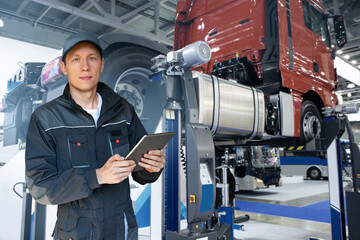 Poster - Serviceman with digital tablet on the background of the truck in the garage	