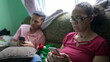 © Marco - Two hispanic family members sitting on couch looking at cellphones. A senior woman looking at phone screen with grandson