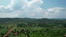 Aerial Drone Shot Flying Towards Tree Covered Hills In The Aravalli Ranges Outside Jaipur With Small Village Town Houses At The Base With Farms And Feilds