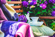 Cup Of Black Coffee On A Garden Chair Next To A Purple Hydrangea Bush