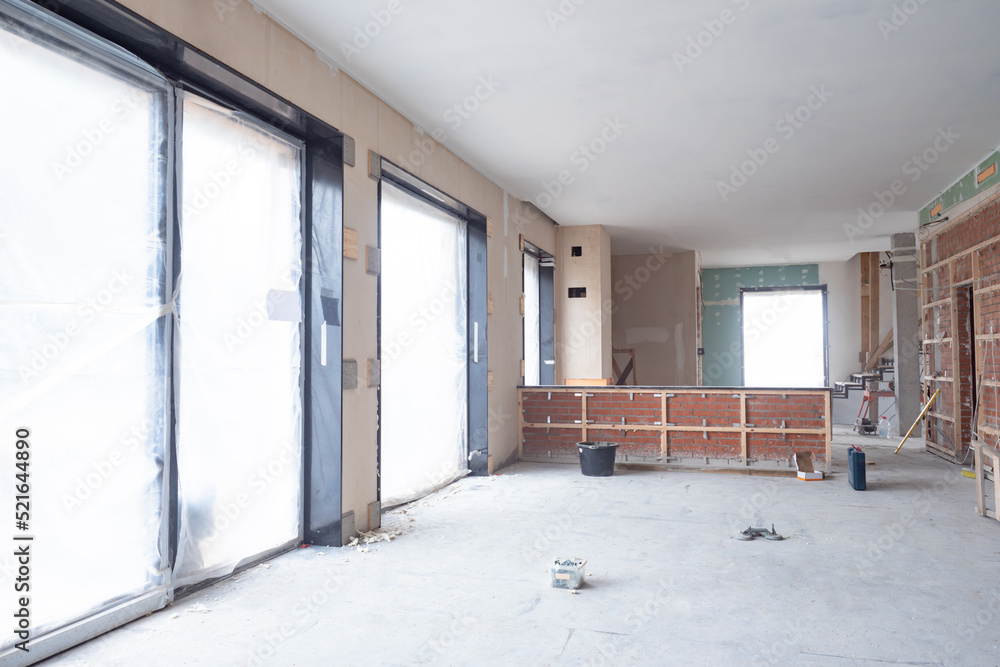 Construction works. Buildings under construction inside view. Final finishing work inside building. Windows renovated building are covered with foil. Spacious space under renovation. Unfinished house