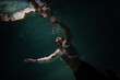 © Ulia Koltyrina - underwater shooting with contrasting light, a guy is swimming underwater, pulling his hand to his reflection in the surface of the water. Subconsciousness and self-reflection, concept