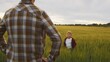 © Acronym - Farmer and his son in front of a sunset agricultural landscape. Man and a boy in a countryside field. Fatherhood, country life, farming and country lifestyle.