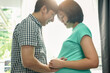 © Chaiyuth - Asian husband stroking his pregnant wife's belly happily