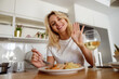 © Kostiantyn - Happy joyful female smiling, waving hand and having pasta dish with shrimps and white wine.