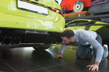 Wall Mural - a man inspecting a newly bought new car in a car dealership