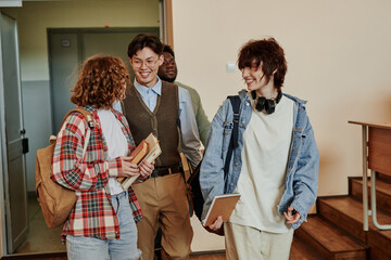 Wall Mural - Happy highschool teenage students in casualwear discussing news while entering lecture hall in the morning or after break