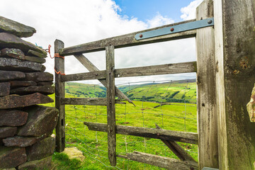  A rickety old farm gate pulled close with orange twine in Swaledale, Yorkshire Dales, UK leading off the high road from Askrigg to Gunnerside over grouse moorland into lush green pastures.