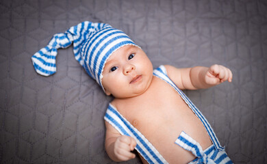 Wall Mural - Small cute baby lying on the bed. Funny portrait boy in hat.