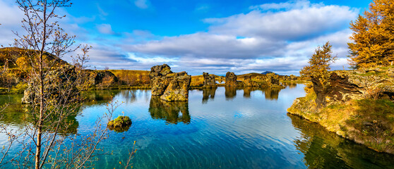 Amazing sunny day on lake Myvatn, Iceland, Europe. Volcanic rock formations reflected in the blue clear water of a volcanic lake. Artistic picture. Beauty world. Travel concept. Panorama