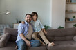 © fizkes - Loving preschooler son hugging young father sit on sofa smile feel happy enjoy leisure together at modern home, pose shooting for camera. Two generation people, good friendly relations, love concept