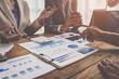 © crizzystudio - Financial analyst analyzes business finance reports on laptop and graph documents during corporate meeting discussions showing successful teamwork, business meeting ideas, marketing.