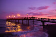 Long pier on the sea in Marbella, Costa del Sol, Spain. Illuminated wooden jetty on a beach in Marbella during sunset. Pier of marbella. Coastal pier into the Mediterranean sea in Marbella, Spain.