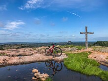 Beautiful View Of A Bicycle Near The Pond And A Wooden Cross On A Sunny Day In Burnet, Texas