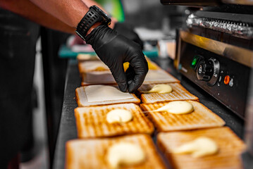 chef hand cooking sandwich with ham, cheese and vegetables on kitchen