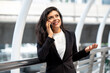 © Atstock Productions - Smiling young Hispanic business woman talking on mobile phone outdoors in the city