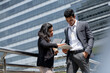 © Atstock Productions - Indian businessman in corporate wear meeting with businesswoman outdoors in the city with office buildings in background