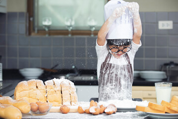 Cute asian boy wearing chef hat apron preparing for baking dough in kitchen at home