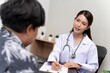 © SKW - A beautiful Asian doctor discusses the condition of a male patient being hospitalized.