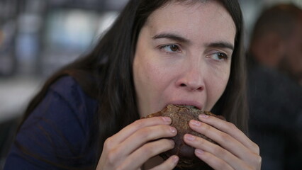 Wall Mural - Woman eating cheeseburger closeup mouth. Person takes a bite of hamburger