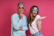 Leinwandbild Motiv Senior mother and adult daughter in funky eyeglasses having fun against pink background